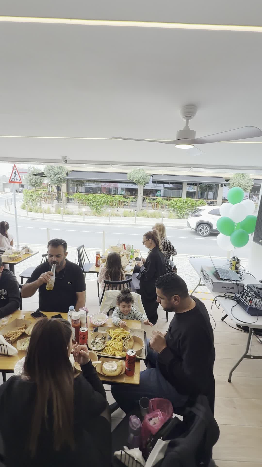 Families and friends gathered at the ASADO Express Paphos opening day, with green and white balloons